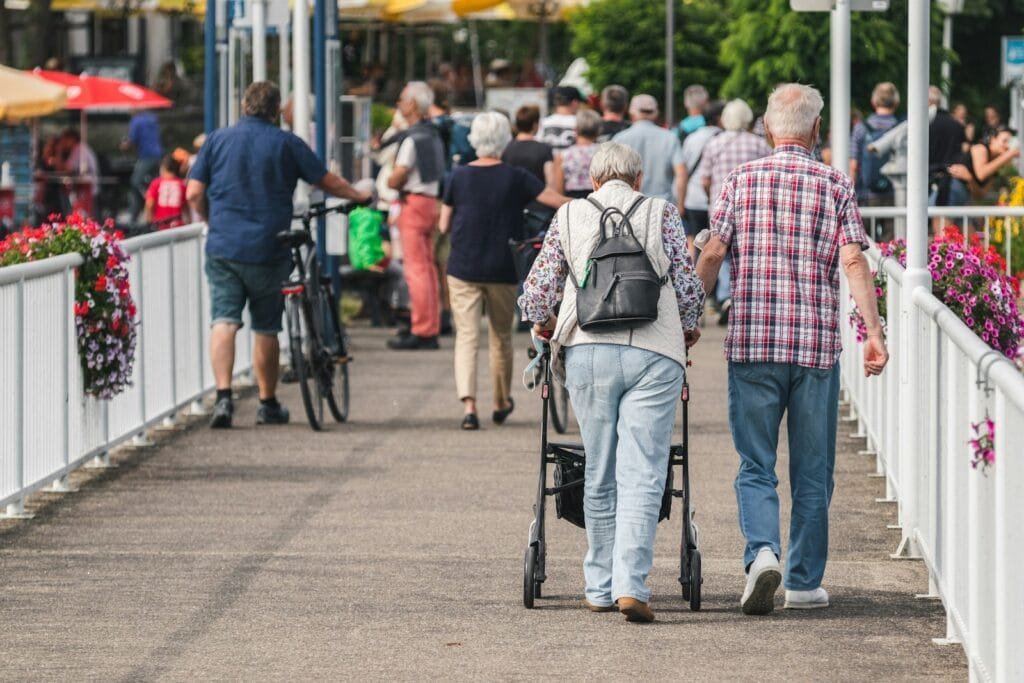 elderly man in brown pants and plaid shirt standing on road during daytime