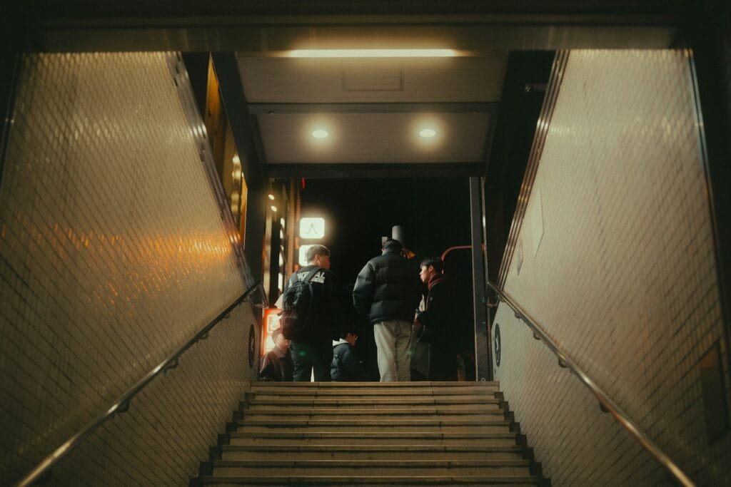 People walk up stairs towards a dark entrance.
