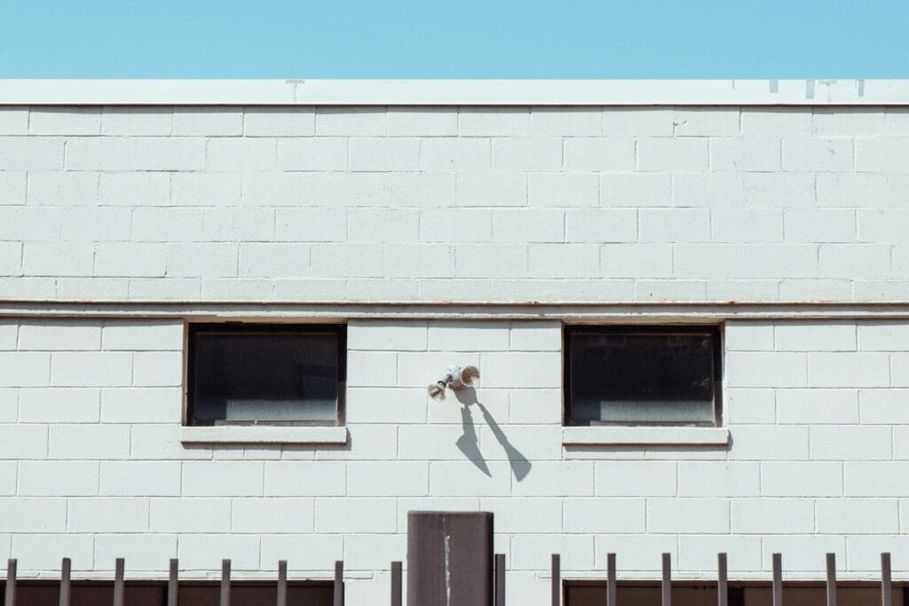 A white building with two windows and a black gate