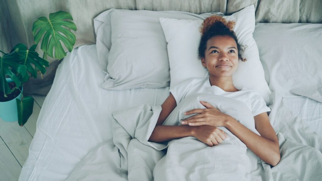 Young woman lying in a white bed and about to get up